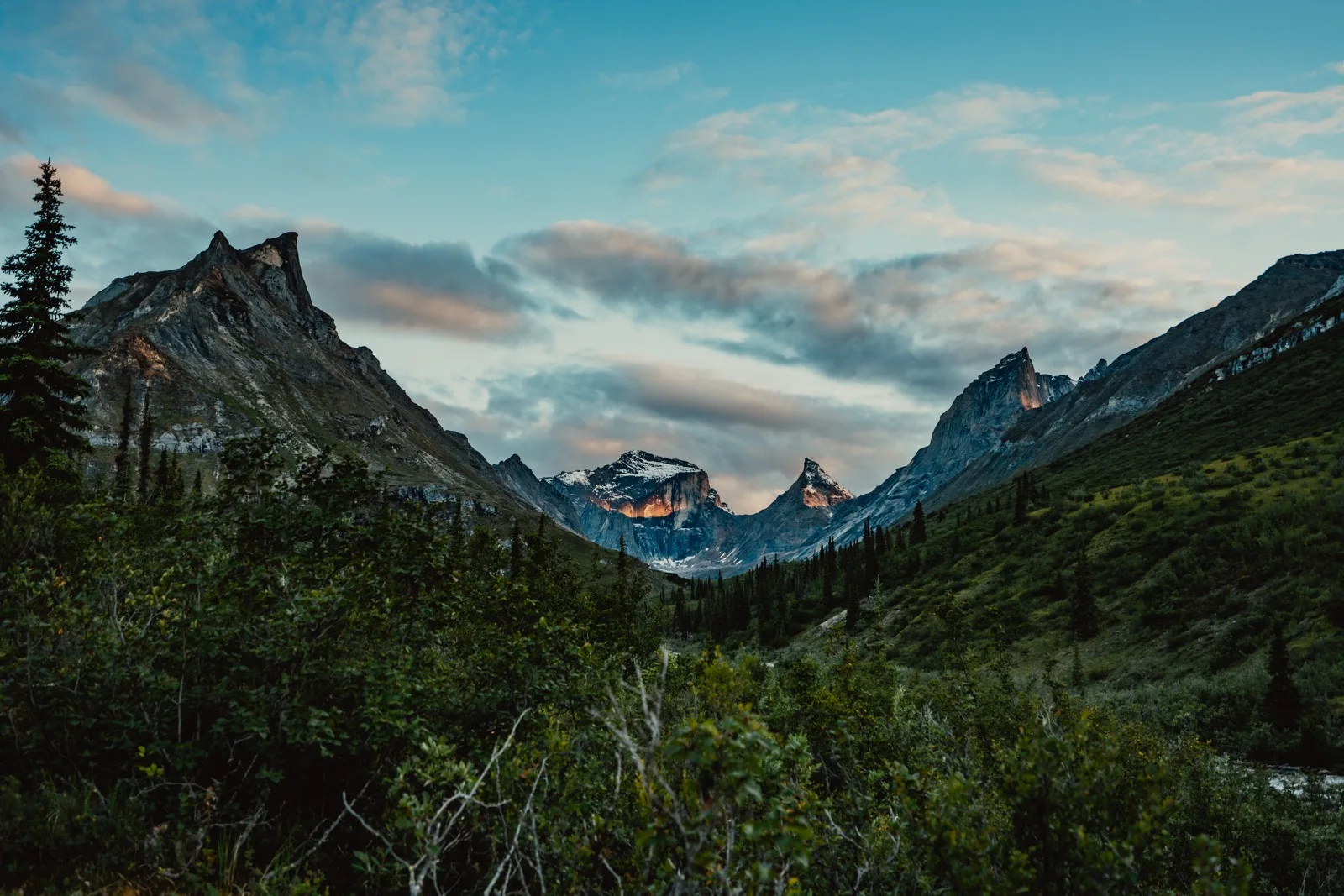 A vast green valley opening beneath clouded mountains