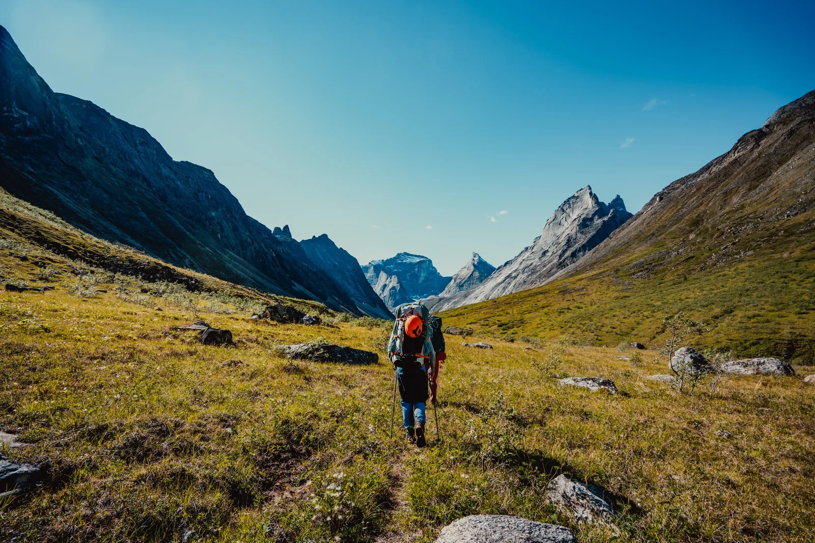 Backpackers crossing the floor of a broad mountain valley