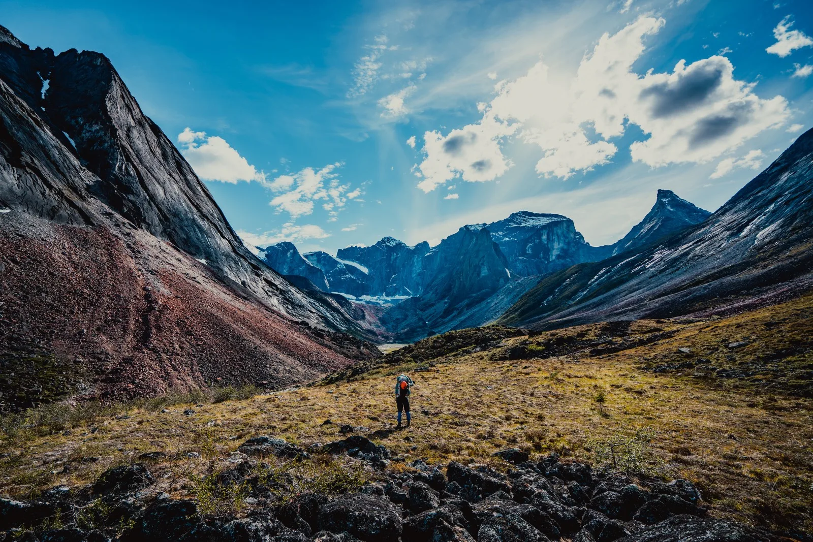A small hiker beneath dramatic mountain peaks