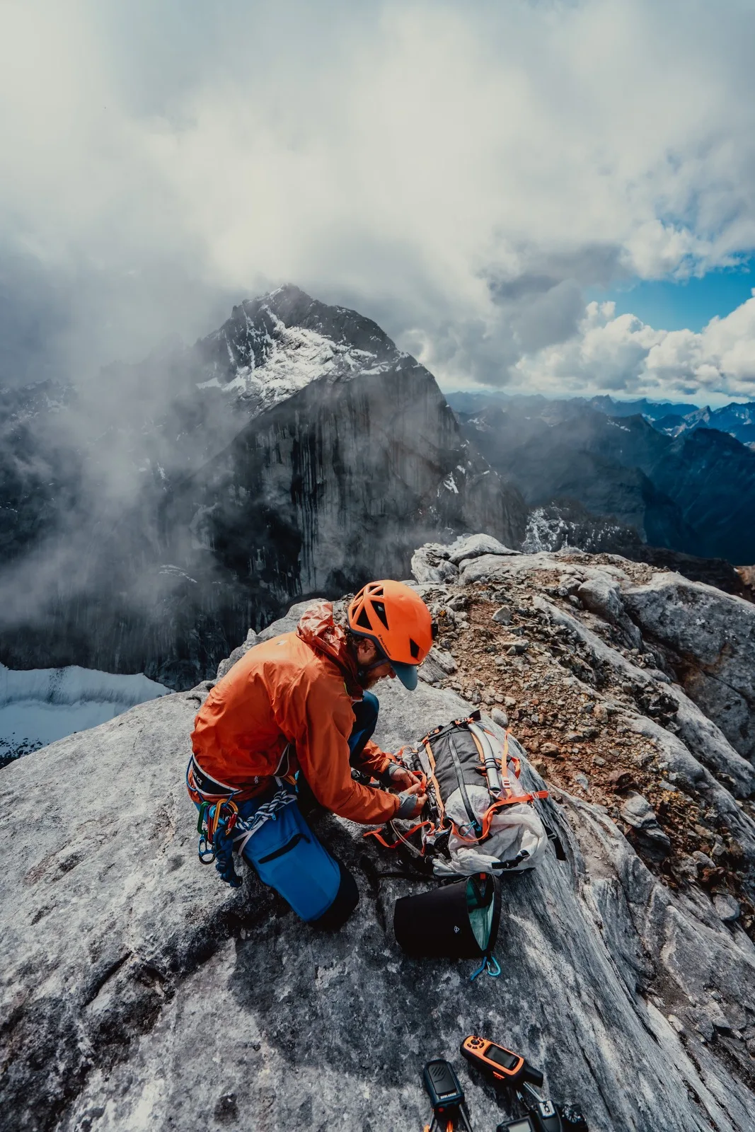 A climber moving beneath a wall of cloud and rock