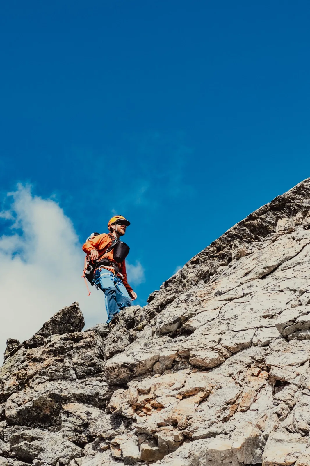 A climber traversing a narrow ridge above the valley