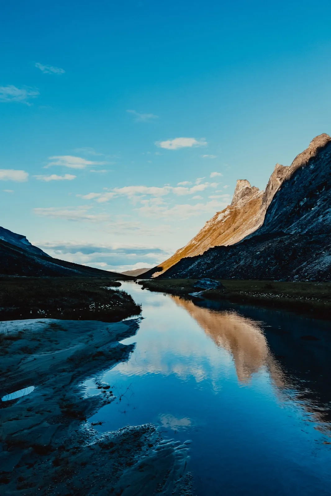A mountain and clouds reflected in a quiet alpine lake