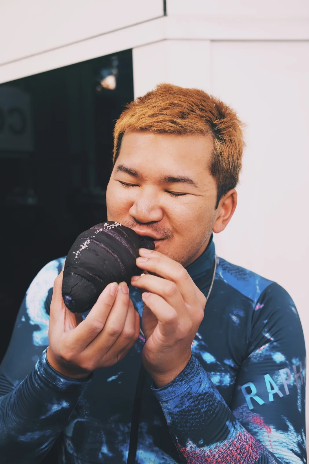A cyclist taking a joyful bite of a dark pastry