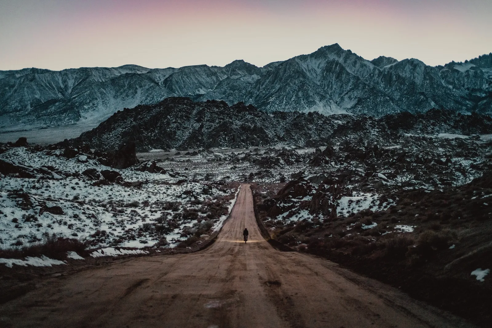 An empty road pointing toward snowy mountains