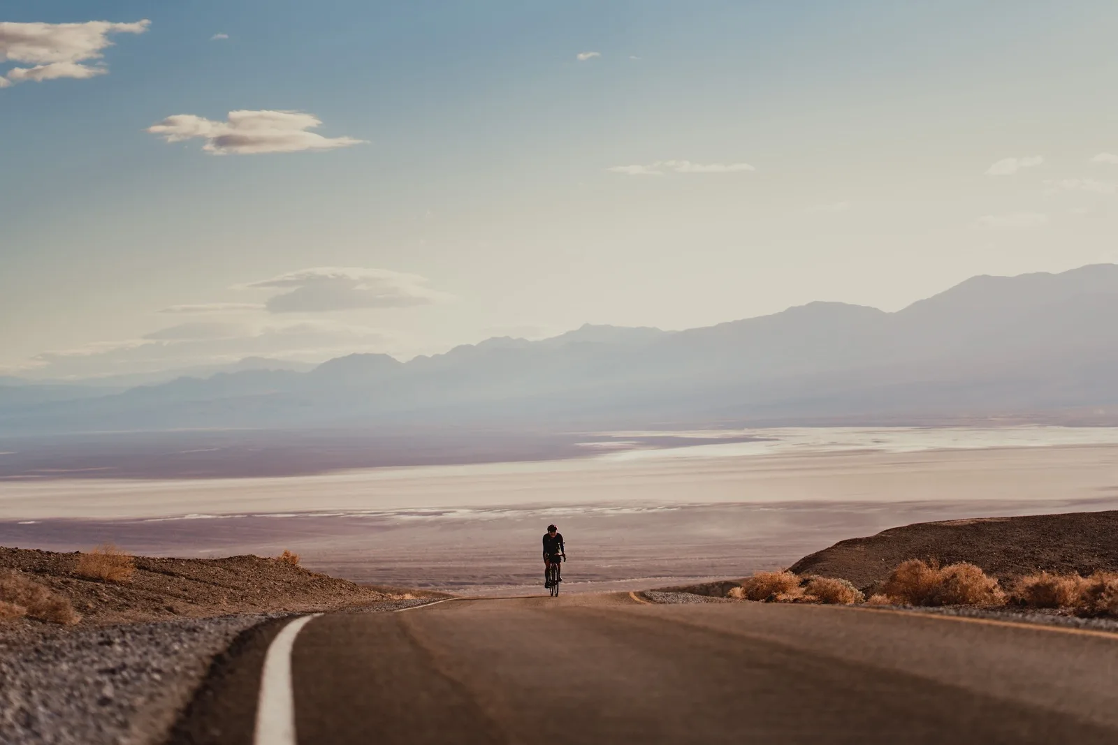 A lone figure above a desert road at dusk