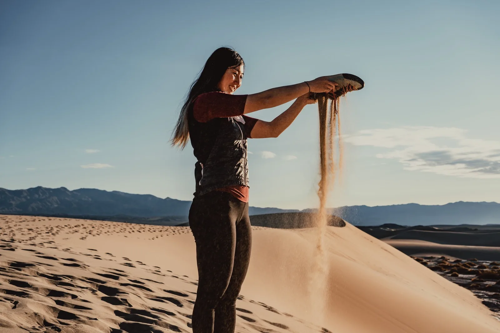 A person pouring sand from their hands on a dune
