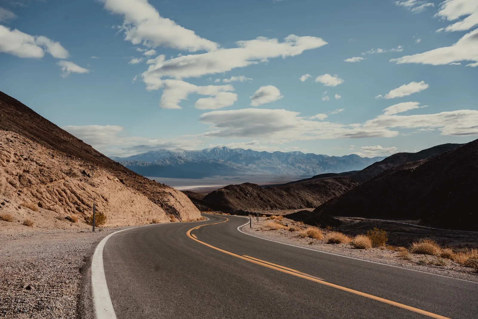 A narrow desert road winding toward a distant valley