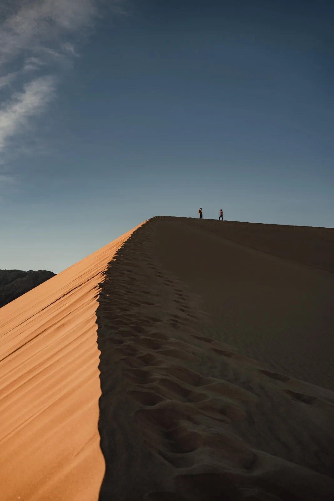 Tiny figures tracing the crest of a sand dune