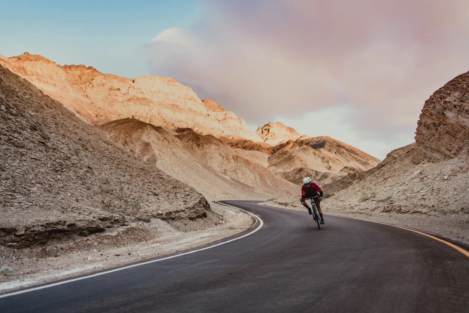 A cyclist climbing a winding road through the walls of Titus Canyon