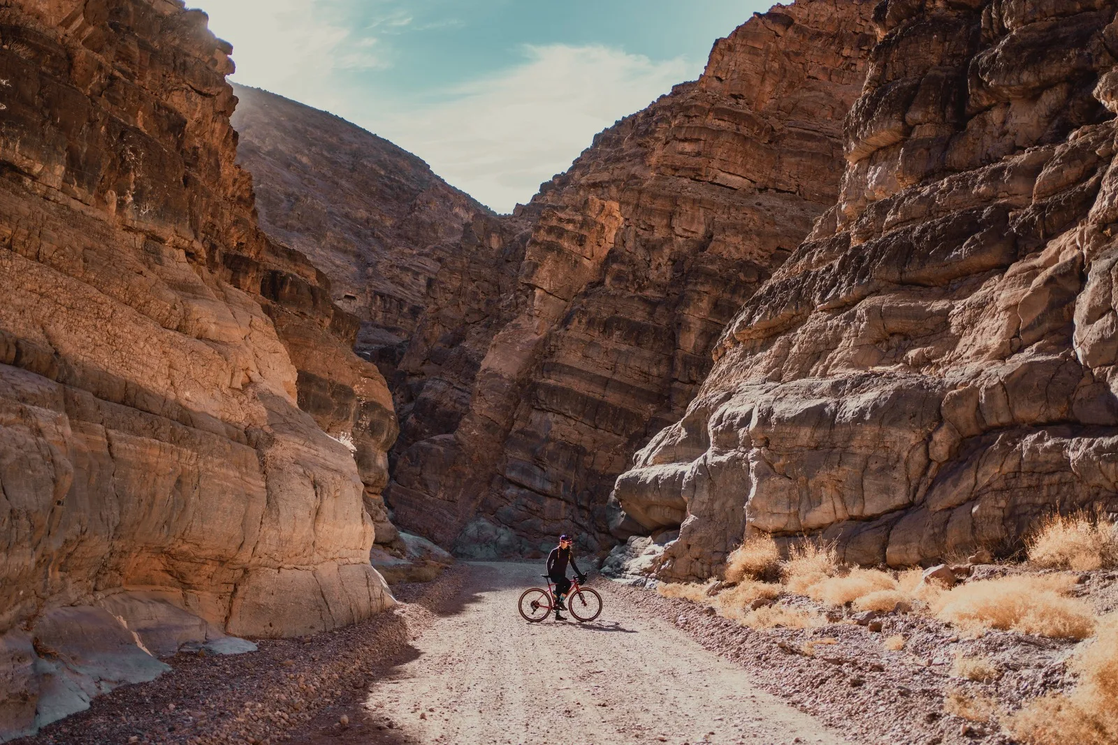 A cyclist pausing beneath the towering walls of Titus Canyon