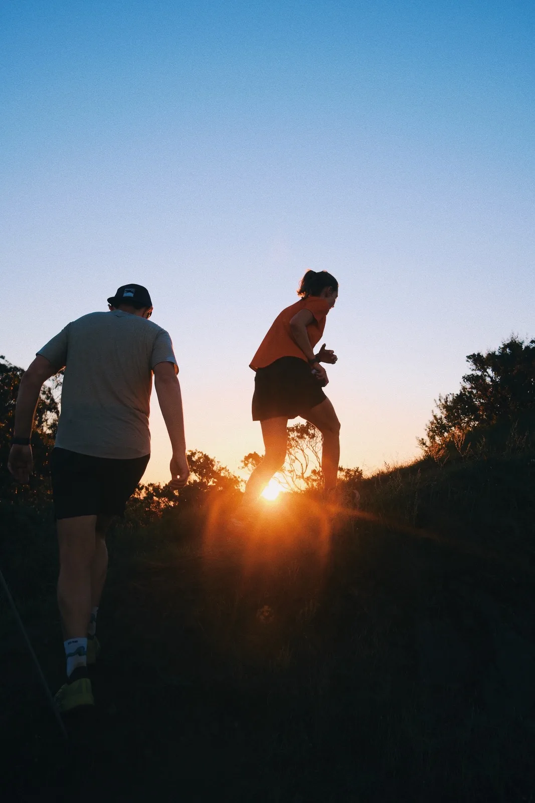 Two runners silhouetted around the setting sun