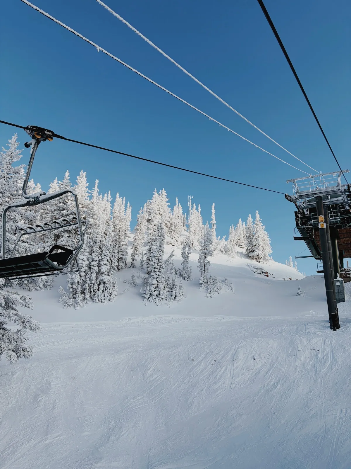 Frosted lift cables crossing a clear blue winter sky