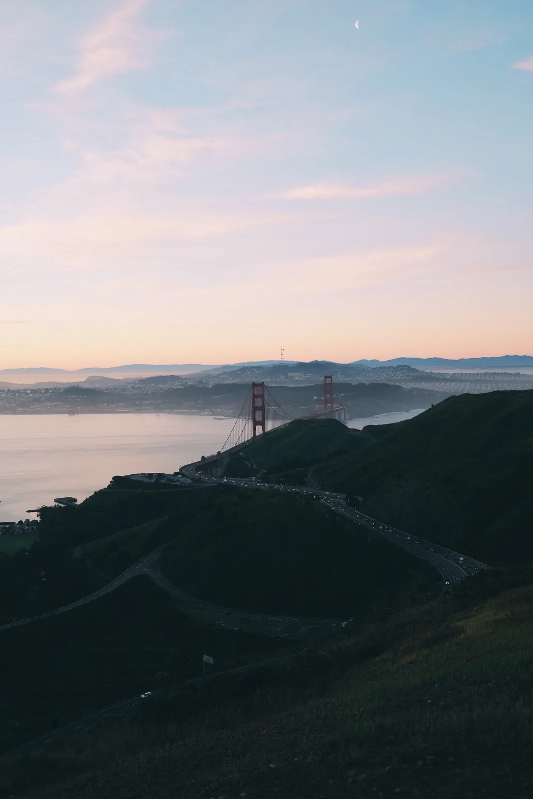 The Golden Gate Bridge beneath a pale morning moon