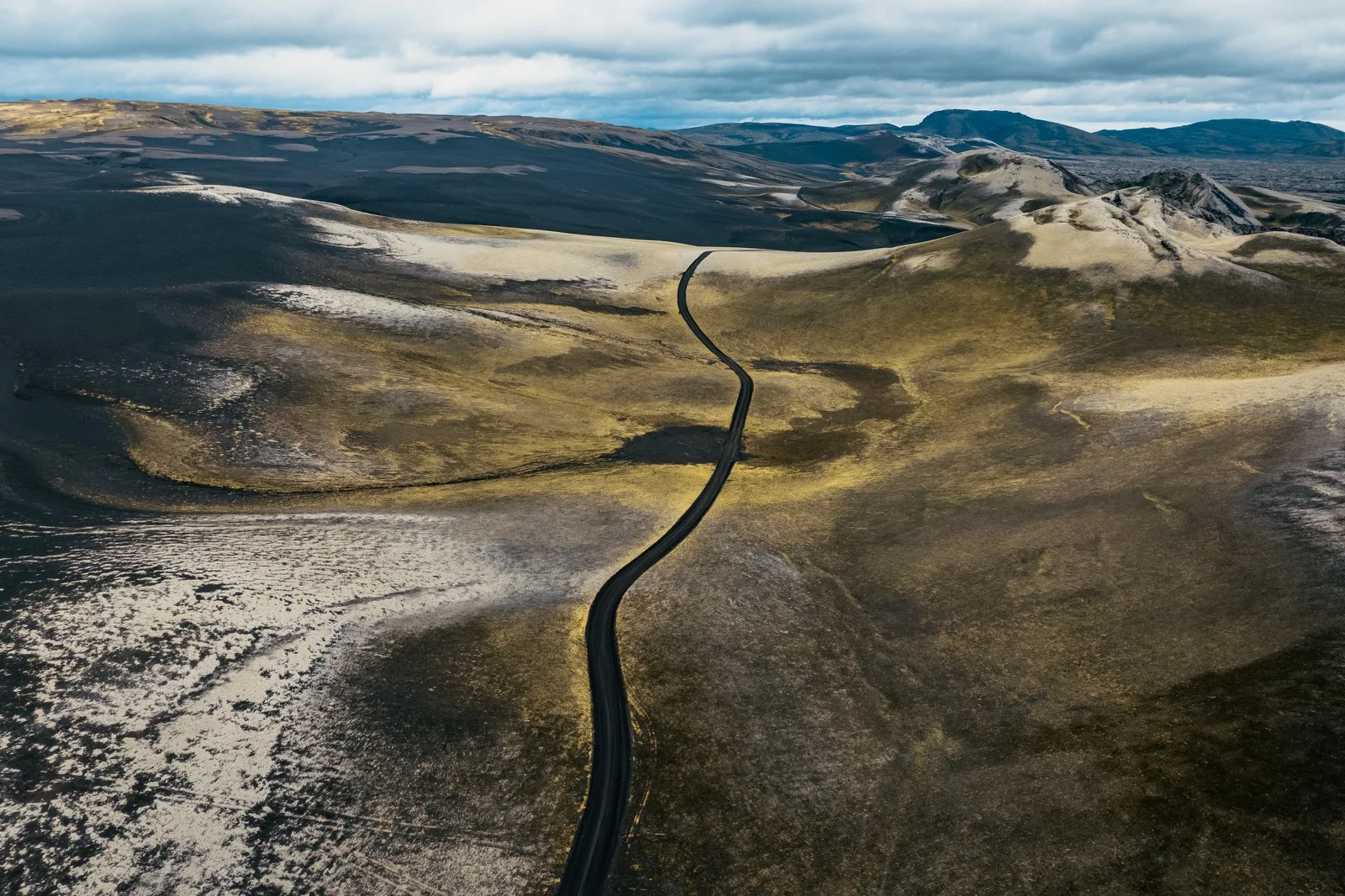 A narrow road winding across dark volcanic land