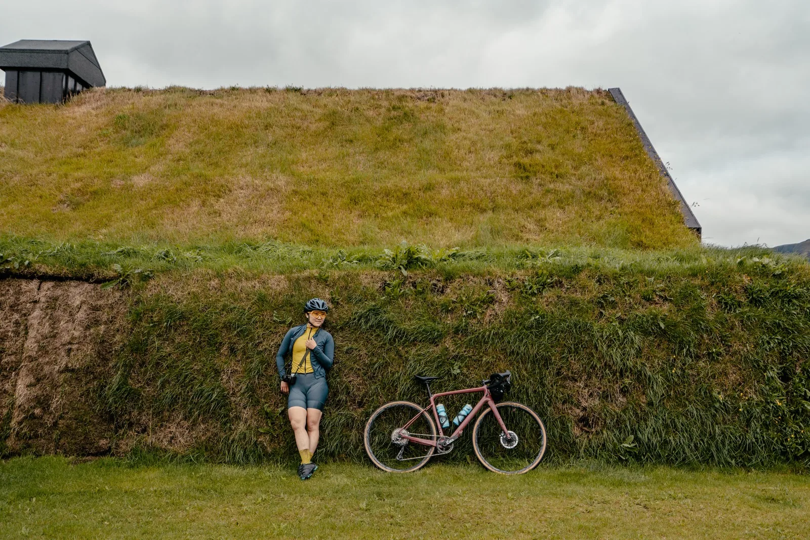 A cyclist resting upside down against a turf-roofed house