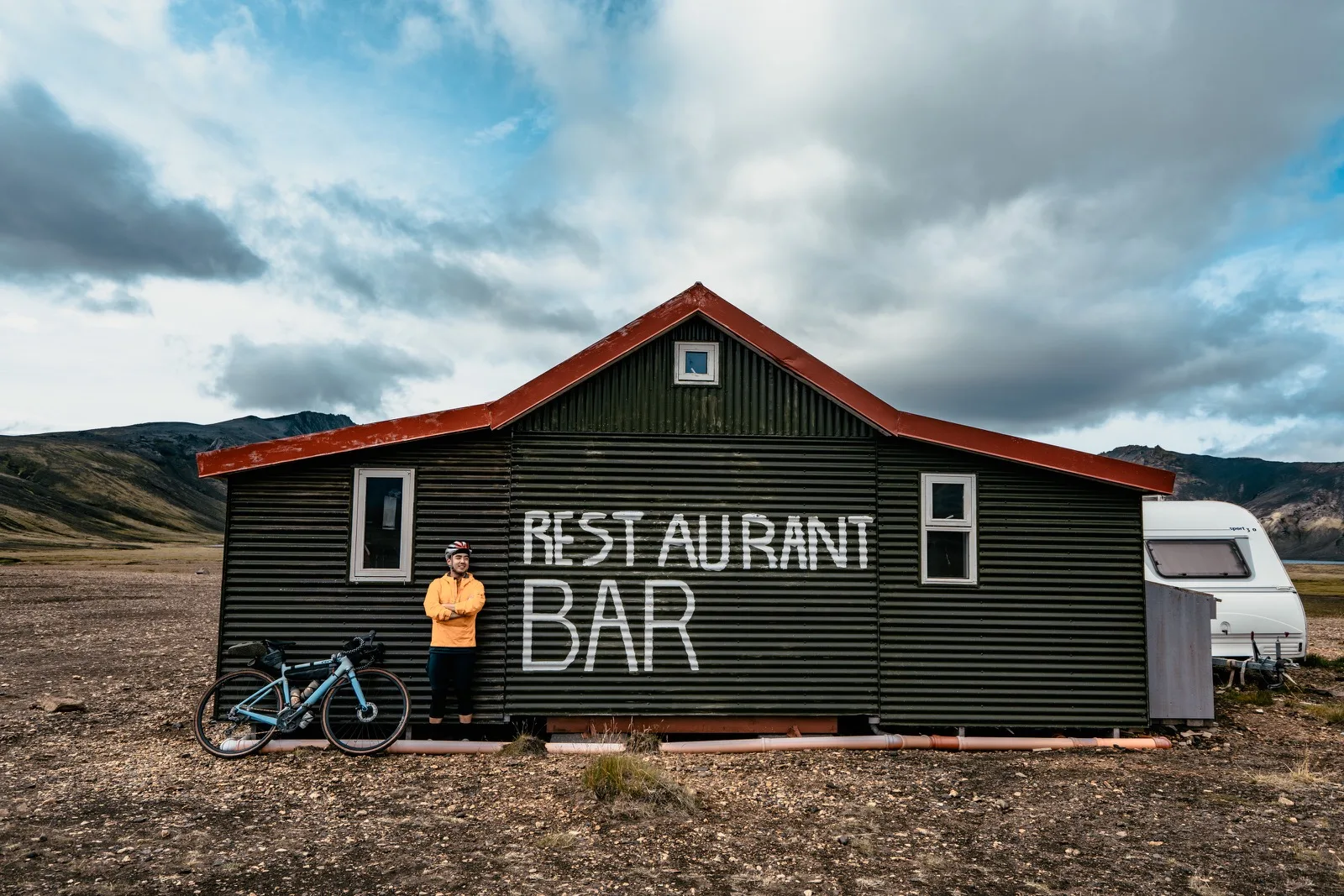 A small roadside restaurant and bar under dramatic clouds