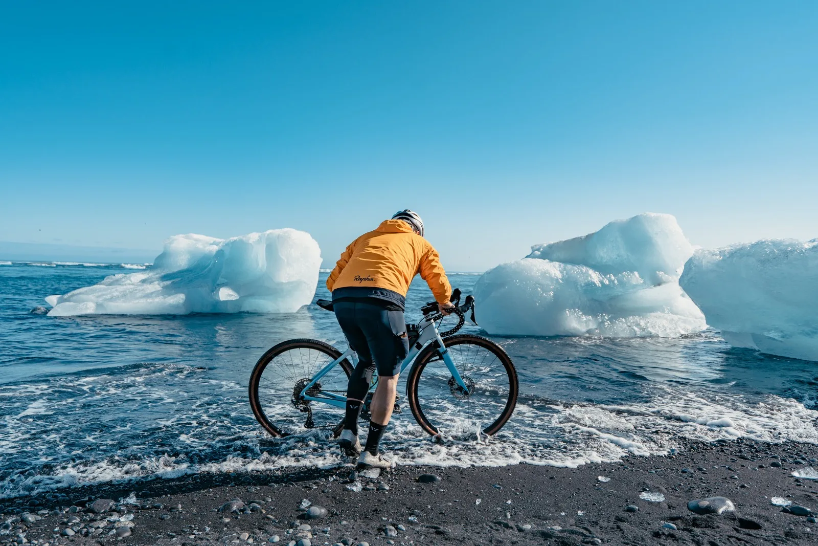 A cyclist riding beside icebergs under a blue sky