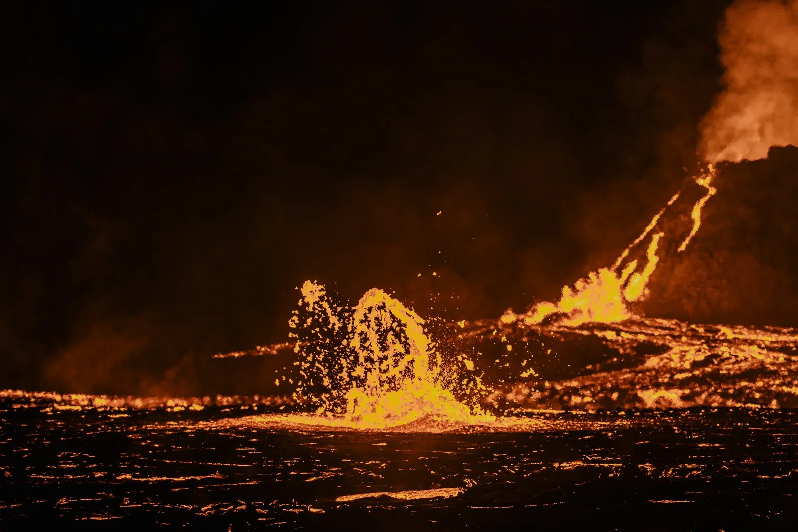 Molten lava splashing from a glowing fissure at night