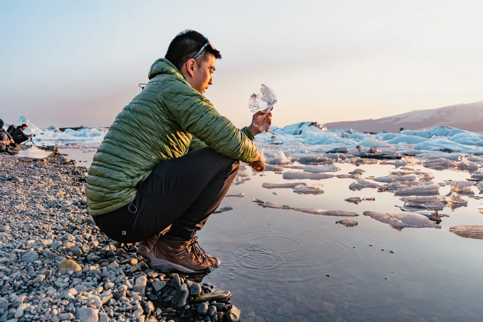 A traveler crouching among pieces of glacial ice