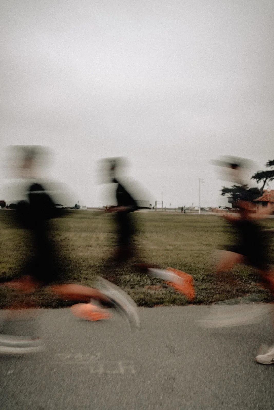 Blurred runners passing a low row of coastal grass