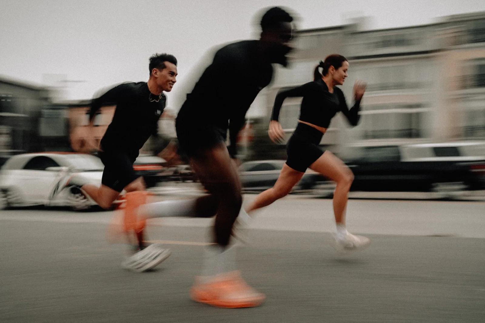Three MRC runners sprinting together through the city