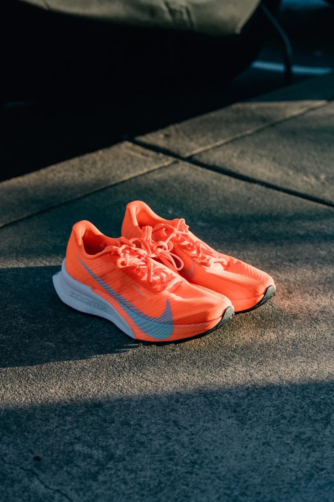 A pair of bright orange trail shoes in sunlight
