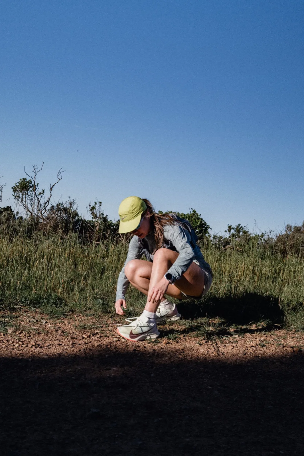 A runner tying a shoe beside the trail