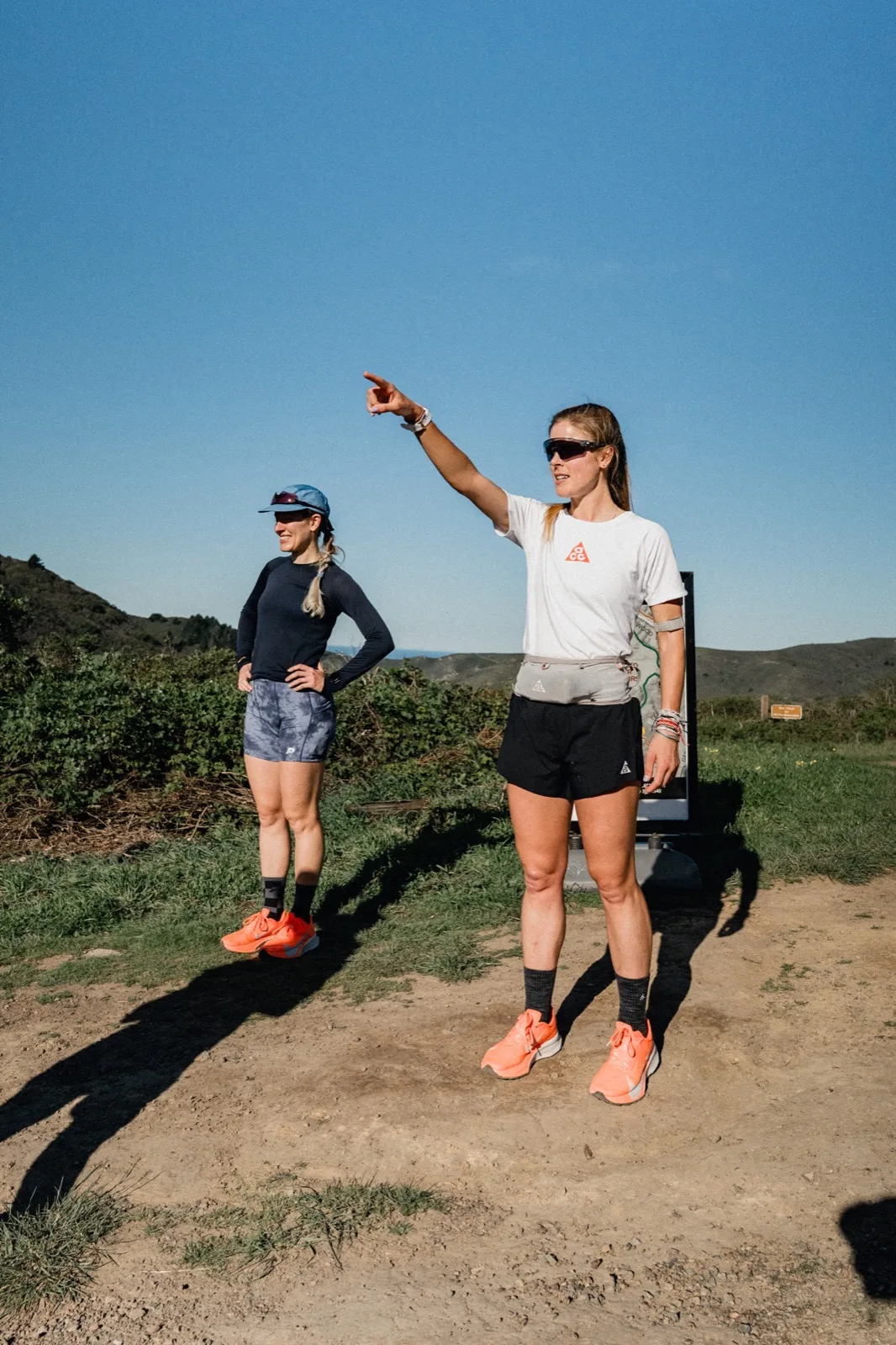Two runners pausing and pointing on a hillside
