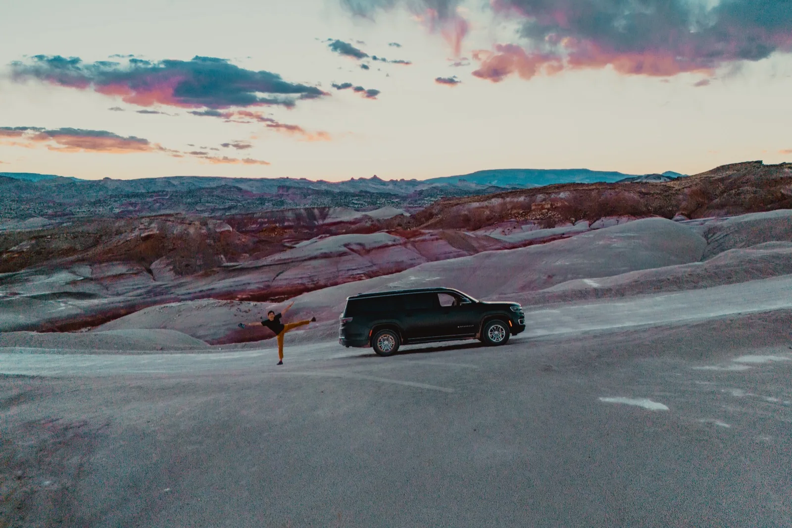 A vehicle crossing a pale sandstone basin at dusk