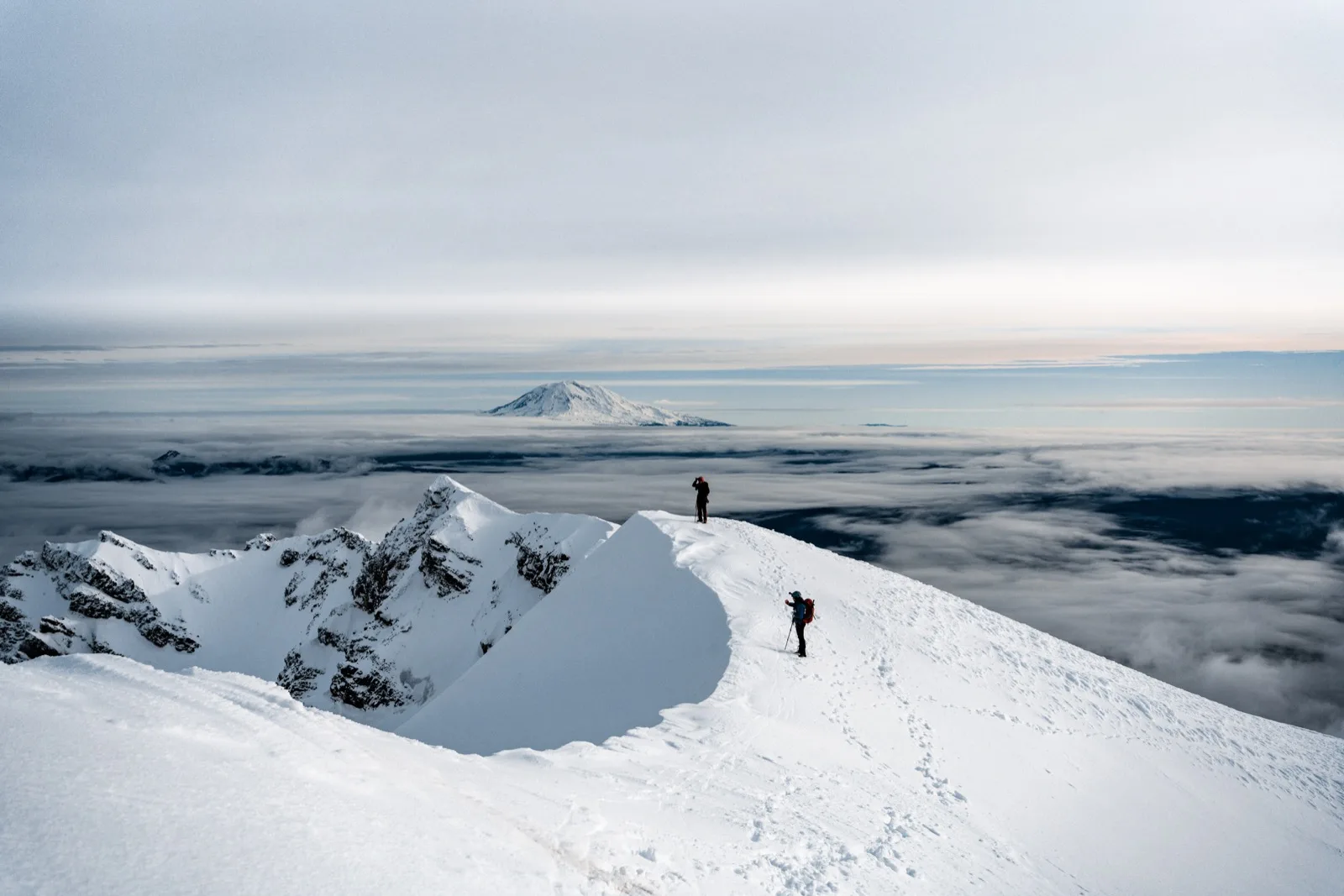 A lone climber on a white mountain ridge