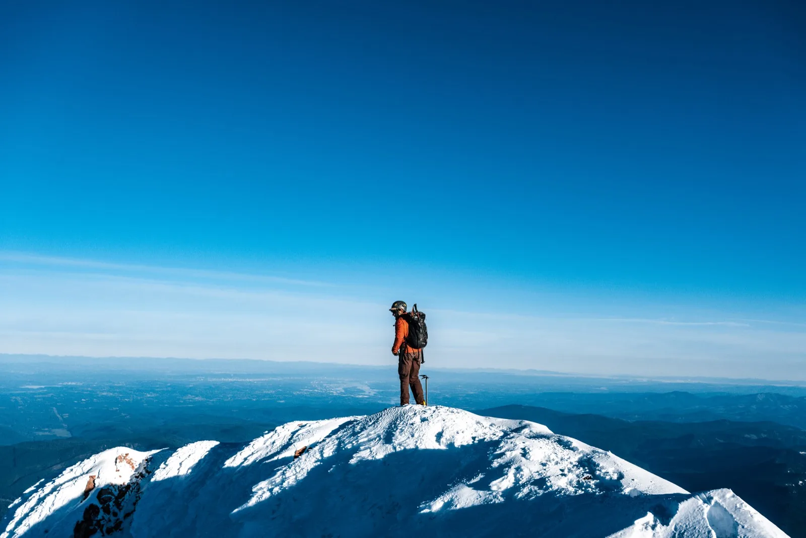 A lone climber standing against a distant blue horizon