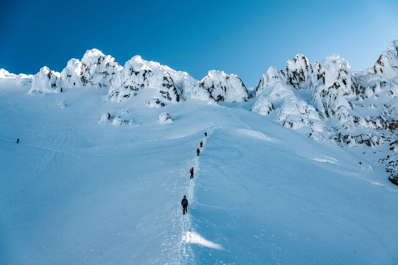 A climber crossing an immense open snowfield