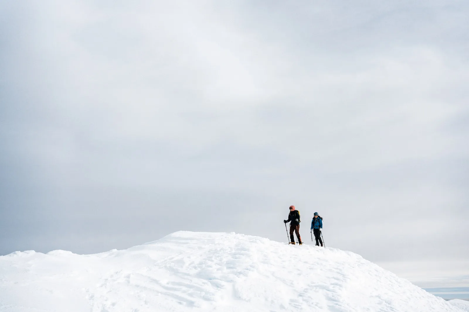 Two climbers reduced to silhouettes on a white horizon